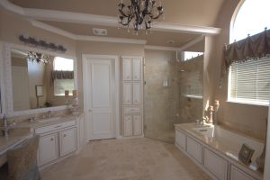 Picture of a stylish bathroom with a chandelier and white cabinetry.