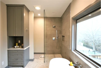 Modern bathroom with glass shower and large window.
