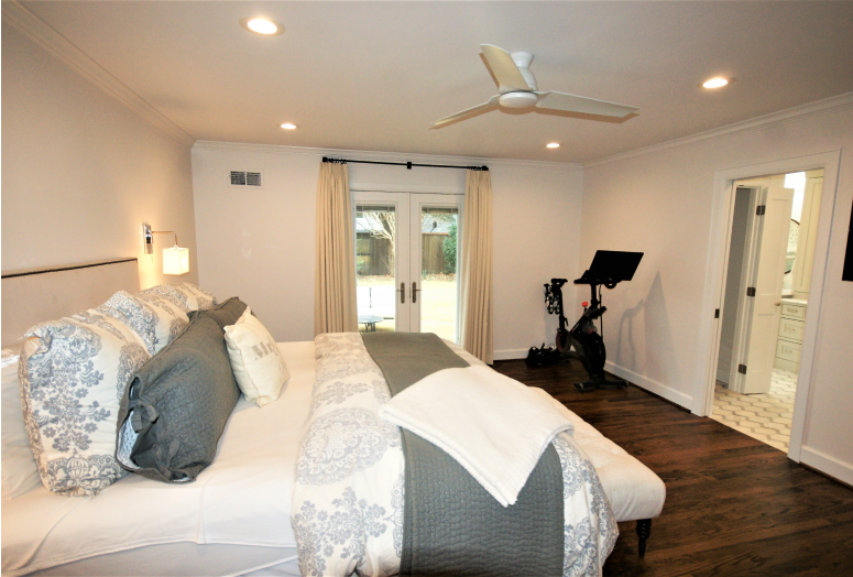 Modern bedroom with exercise bike and ceiling fan.