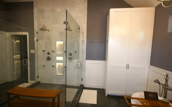 Modern bathroom with glass shower and white cabinets.
