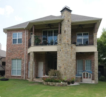 Two-story brick house with chimney and lawn.