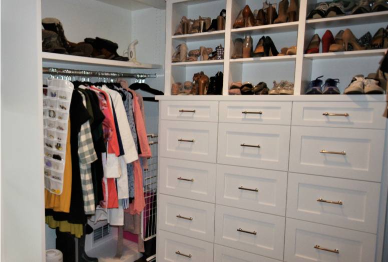 Organized walk-in closet with clothes and shoes.