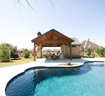 Backyard pool with pavilion and trees.