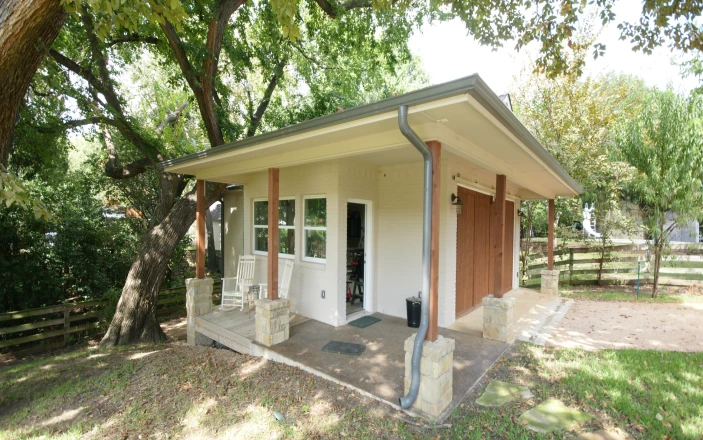 Cozy small house surrounded by trees and grass.