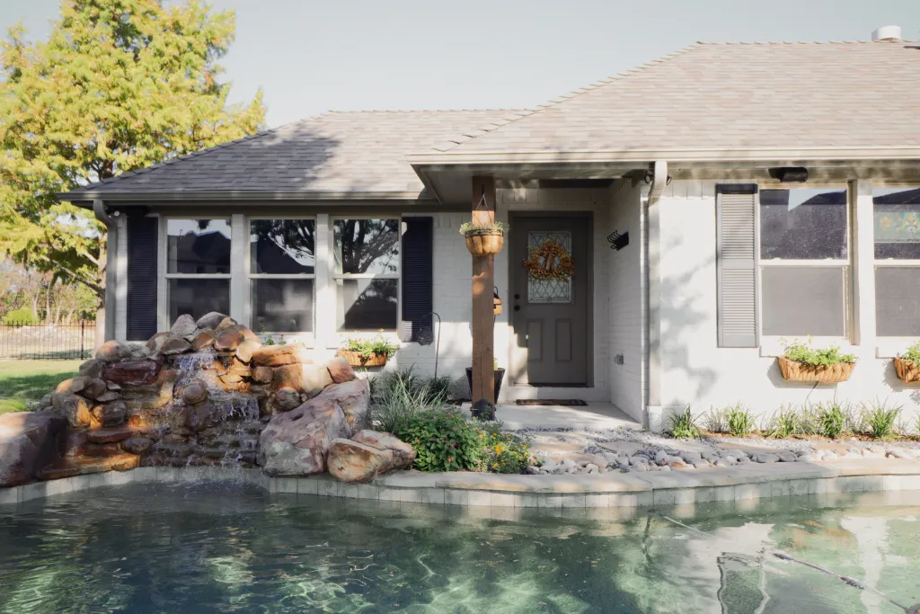 House with rock waterfall and pool in garden.
